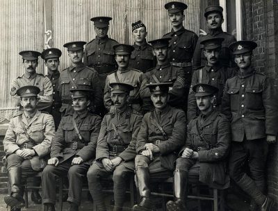 A group photo of British soldiers in the first world war, sitting on chairs and standing behind one another. The photo is in the style of a Chinese artist but without any Chinese characters. There are no repeated words or obvious spelling and grammar errors.