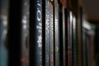 Closeup of book spines with the title "G 있다는/cc AST lineNumber" written on them, on a shelf in a library, with a blurred background, creating a dark and mysterious atmosphere, taken as a close up, macro photograph, with high resolution.