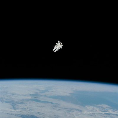 A small astronaut floating in space, seen from the edge of earth's atmosphere against a black background, wearing a white spacesuit with the earth below the horizon in a minimalistic and simple clean style of photography.