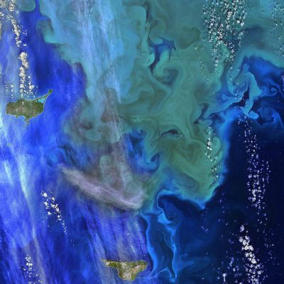 The remote satellite photo of the art in the southern tropical sea, is seen above and to its right as it forms an intricate pattern of blue and green water near islands. The closeup view reveals the vibrant colors of greens, dark grays, light greens, and white that make up the art too, with swirling patterns resembling ripples or waves in the style of Vector. A thick band around the top left corner could represent land features, while smaller details like particles can be visible inside the water's surface.