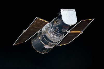 Aerial view of the Hubble Space Telescope floating in space against a black background in isolation.