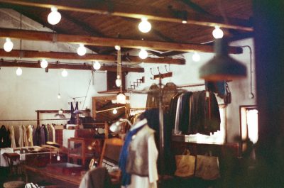 A photo of the interior of an industrial  store, wooden beams and white walls, hanging lights in the ceiling, on mannequins, vintage camera flash photography, Lomography Color Negative film, gritty texture