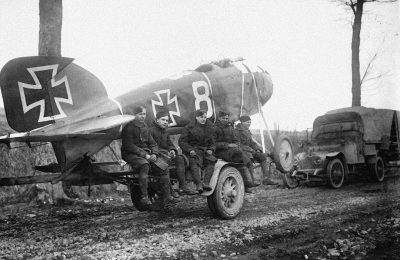 german soldiers sitting on the wing of an al – ultra one plane, painted with white "8" and black cross, near by is parked old truck with large gun, late autumn day in western germany, 20th century photo from camera obscura