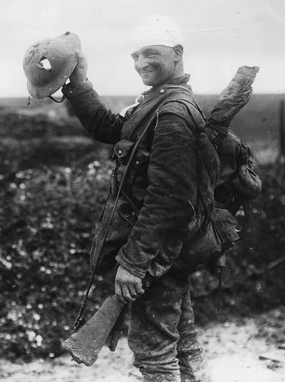 A happy British soldier wearing World War I  and helmet, with his hand raised to the sky holding up an old rifle on one shoulder while carrying two large bags of salt crystals in other arms, black & white photograph, 50mm lens, f/2