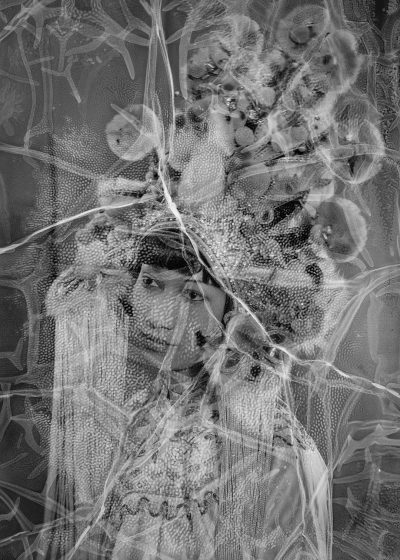 luminogram of an abstract photograph with the face and body shape in double exposure of man covered by spider webs, the skin is covered with spores, he wears traditional made from plastic foil and fabric and long hair is decorated with flowers and lace, the background shows watercolor patterns, the composition includes organic shapes, textures and patterns, the light forms a soft glow effect on parts of his form, the overall mood evokes calmness and dreamy quality