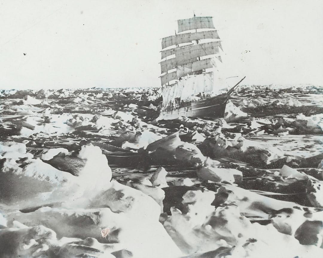 vintage photo of an old sailing ship stuck in the ice, surrounded small and large blocks of snowcovered rocks, winter landscape, polar environment, early photographic style, very worn out and damaged photo in the style of early photographers.