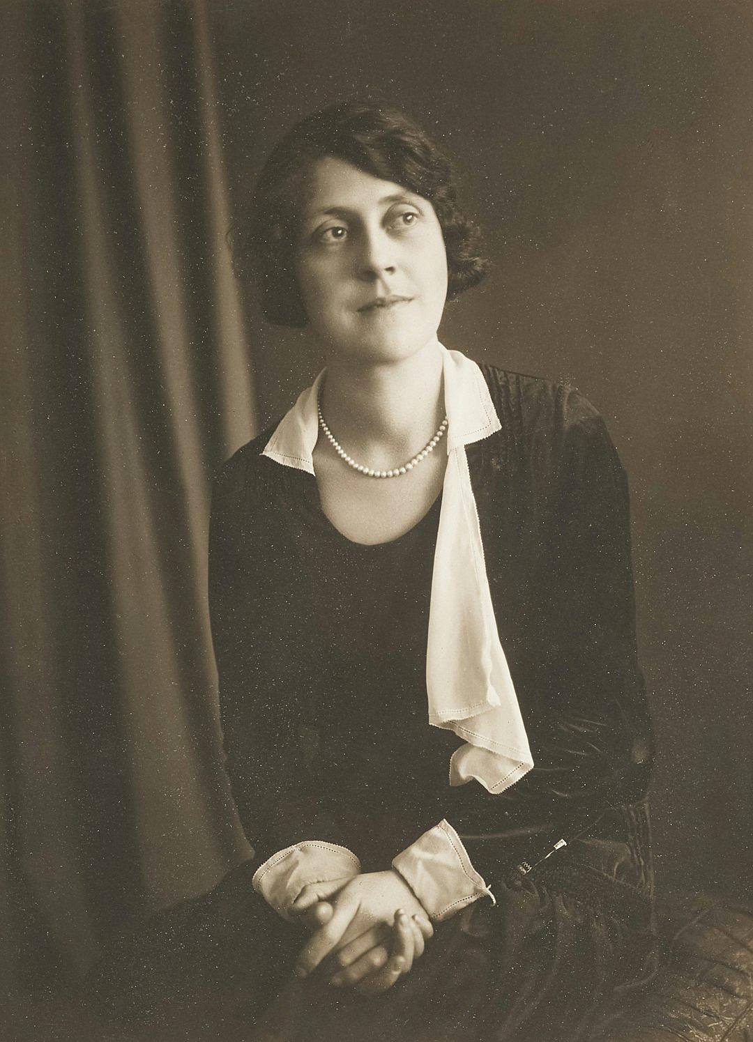 A portrait of Lady Maria Peckwater in her early twenties, wearing a white tie and black dress shirt with a pearl necklace, in the style of a vintage photograph.