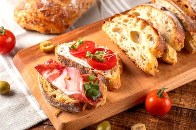 Sota de canó, with tomato and ham on a wooden board with bread slices. Food photography in the style of Sota de canó.