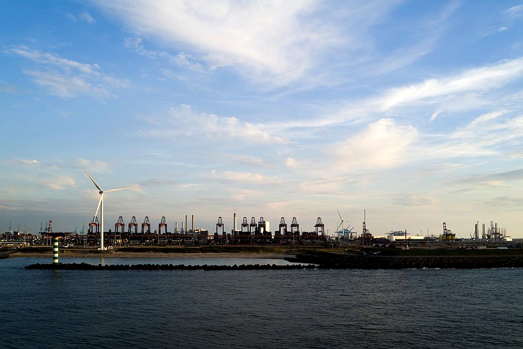 View of a port in Japan with wind turbines and industrial buildings, blue sky with white clouds, photo taken from sea level, wide angle lens, landscape photography, in the style of unknown artist.