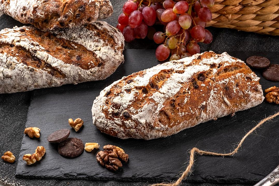 Sour dough bread with walnuts and chocolate, grapes on the background, food photography, high resolution