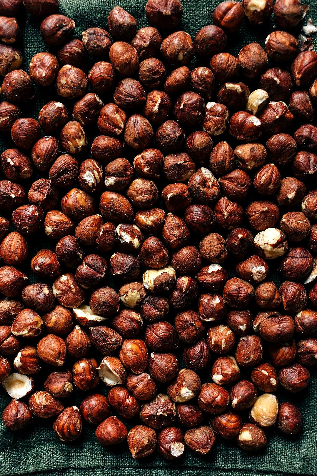 close up photo of scattered hazelnuts on green fabric, shot from above, studio photography, soft light, low contrast, warm colors, natural lighting, product photography style, high resolution