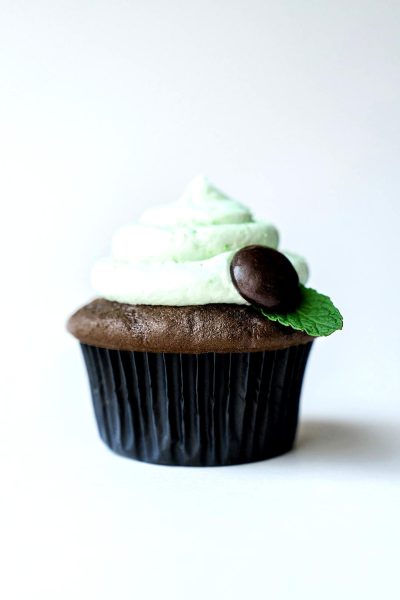 Mint chocolate cupcake with mint leaves and green cream on white background, closeup photo