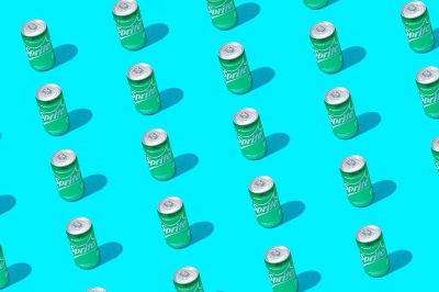 Cans of green sparkling soda arranged in an isometric pattern on a blue background, a seamless repeating texture, a flat lay, high resolution photography, hyper realistic in the style of stock photo.