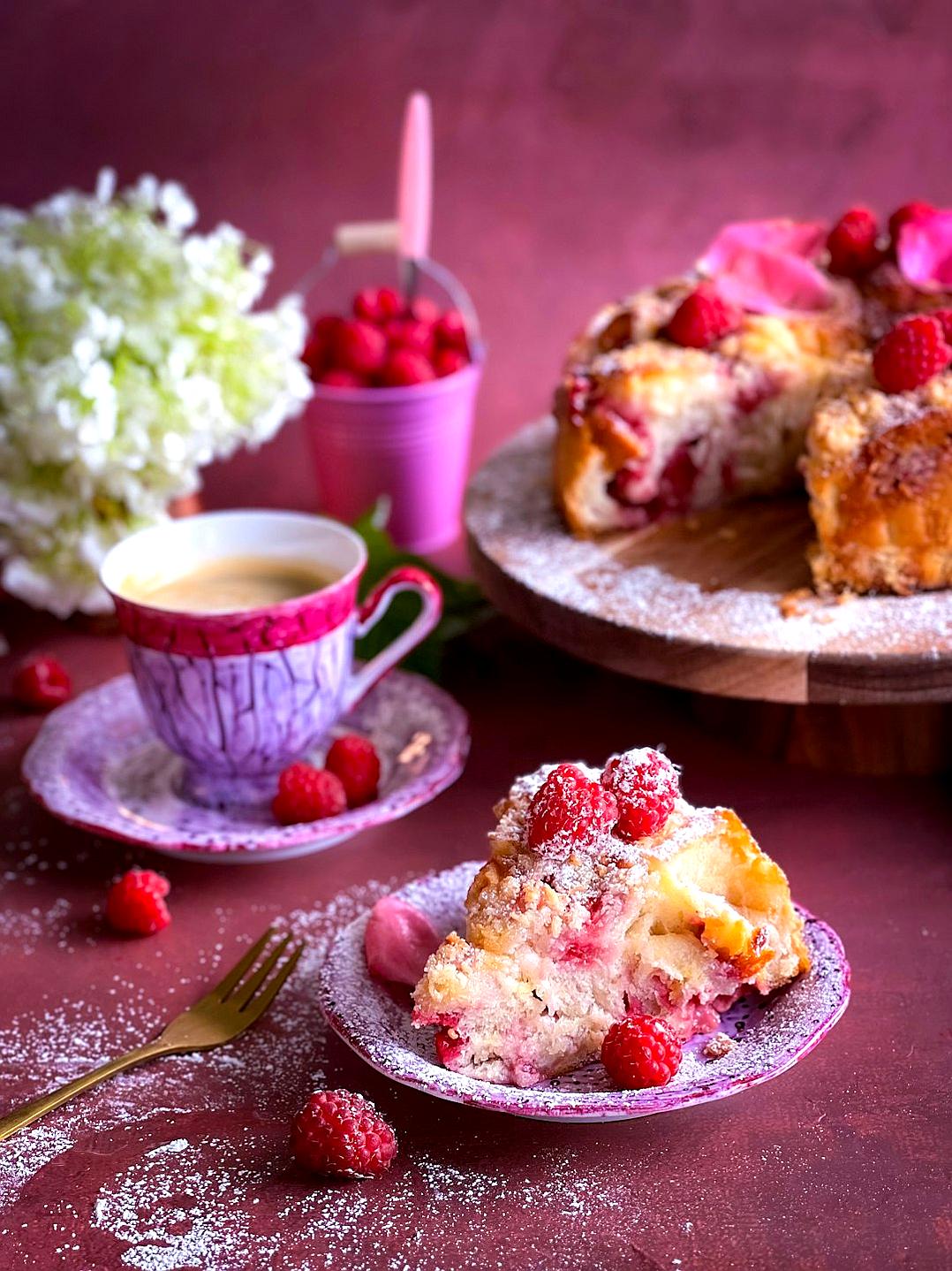 A slice of delicious raspberry coffee cake on the table, surrounded by beautiful flowers and cups with pink color tones, creating an atmosphere full of warmth and romance. The photo was taken using a Canon eos r5 camera, and the background is a dark red. It features a high resolution photography style in the style of beautiful lighting effects adding depth to the composition. This image has been created in ultrahigh definition.