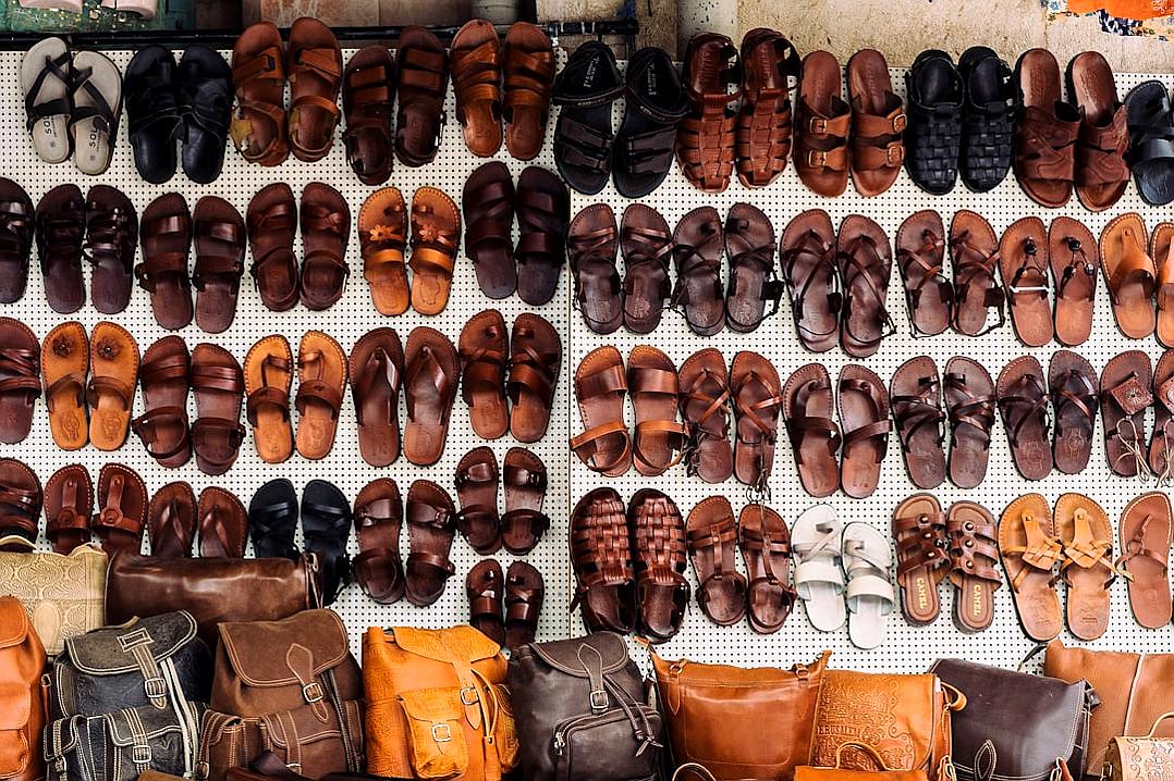 A wall full of leather sandals and brown backpacks in an old Indian market, wide angle shot, in the style of unsplash photography.