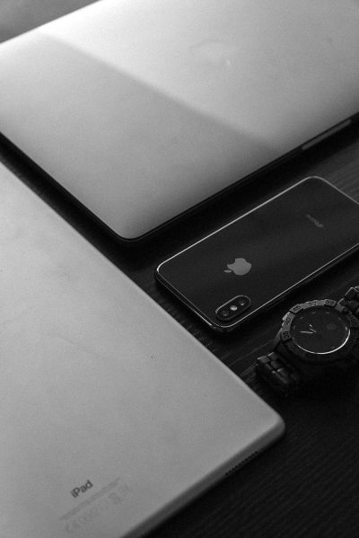 Black and white photography of an iPhone, macbook laptop and watch on the desk in the style of.