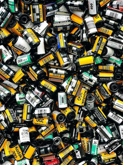 A pile of film canisters from the 1990s, with yellow and black labels on them, arranged in an aesthetically pleasing manner. The background is white to highlight each object clearly. There are no text or graphics on any canisters; they just have their colors and logos. This photo was taken in the style of professional photographers using high-quality cameras.