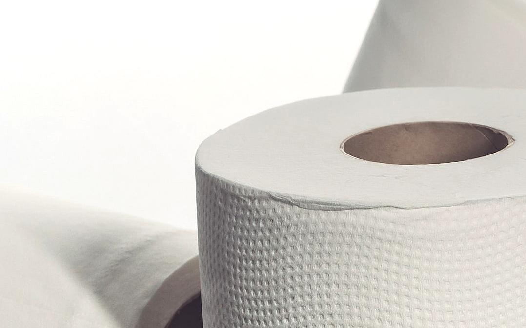 Close up of a white toilet paper roll on a table. A closeup, high resolution photograph with a white background in high definition.