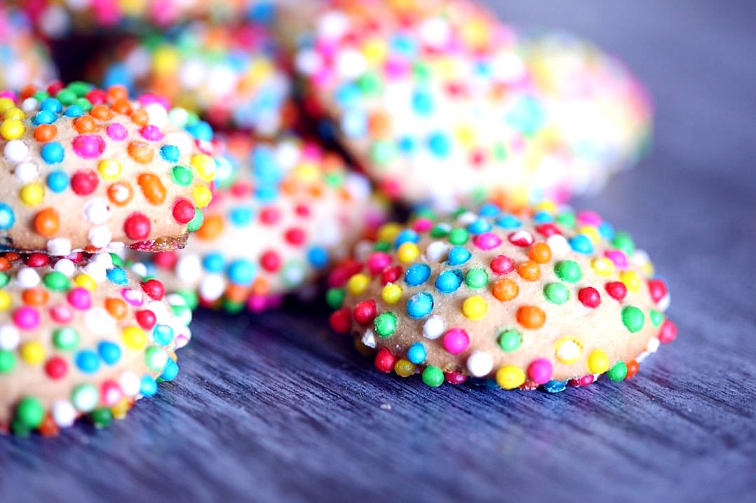 Closeup of colorful sprinkles on small cookies, high resolution photography, in the style of Canon EOS.