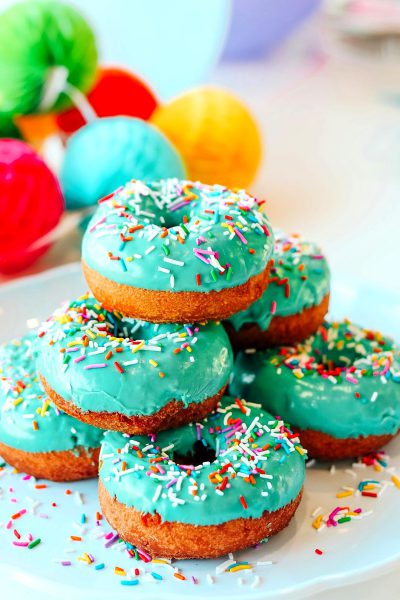 easter themed donuts with turquoise frosting and sprinkles, on white plate, surrounded by e HD