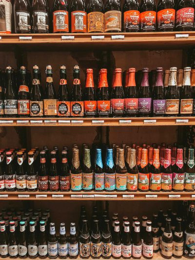 A shelf with various types of beer in different colors and styles, including bottle labels showing the name 'Or décourge', and other signs indicating their location and base crime. The shelves have an array of bottles from small to large sizes, creating depth on the wall. There's no text or symbols visible on these bottles except for product logos and product photography, highlighting them as prominent elements within each collection.