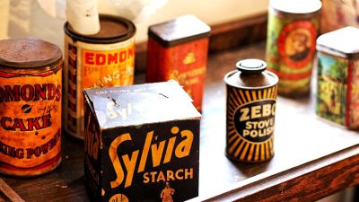 A vintage kitchen counter with an oldfashioned box of "Sấyia Starch" and several antique cans labeled as Z TOURMcent L engaged in various uses, including one can featuring the text 'Zstatement’ , vintage style, warm colors, nostalgic atmosphere, closeup shot.