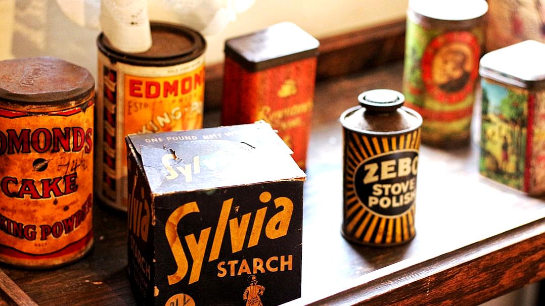 A vintage kitchen counter with an oldfashioned box of “Sấyia Starch” and several antique cans labeled as Z TOURMcent L engaged in various uses, including one can featuring the text ‘Zstatement’ , vintage style, warm colors, nostalgic atmosphere, closeup shot.