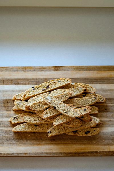 Sasieries cut into strips, placed on the table in front of them is an unlit wooden board, which was used to create beautiful Biscotti cookies. The whole scene gives off freshness and vitality, with natural light creating soft shadows that highlight each piece's intricate details. This photo captures one of my favorite moments from food photography.