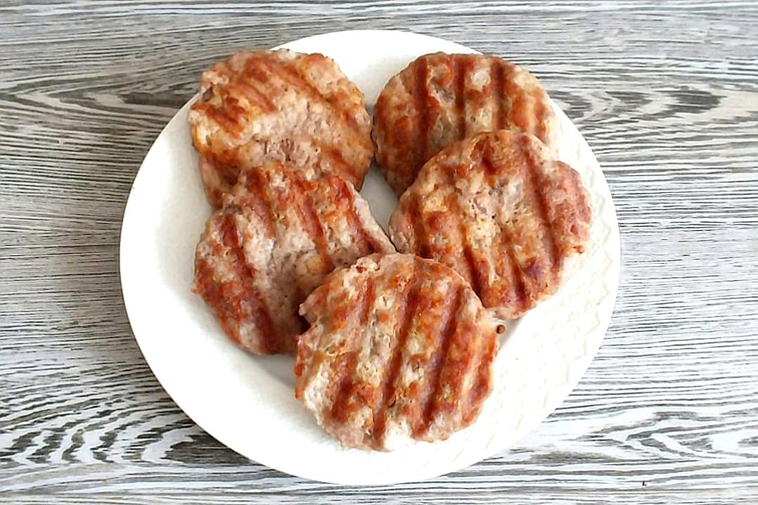 Grilled birds with marks on the surface, each on their own plate, arranged neatly together on top of an empty white table. The meat is light brown and has visible pink coloration inside. It’s placed against a gray wooden background to highlight its texture and colors. This aerial view captures every detail of these delicious ground turkey shaped falafel patties, making it look mouthwatering. The subdued colors are in the style of Mangy Droganin ehl philanthhire K.