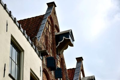 Close up of a brick house roof in a small town centre with a sky view, commercial photo stock photography taken on a Canon EOS R5, low angle side perspective view, Dutch architectural style, Flemish Golden Age style buildings.