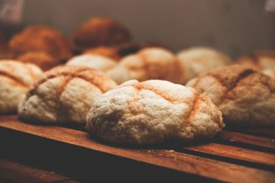 A close-up shot of freshly baked sourdough bread rolls on display at the bakery, highlighting their golden brown crust and delicious texture. The background is blurred to emphasize these fresh buns, creating an attractive visual. The image has a quaint simplicity, with light and dark amber tones, soft lighting, warm colors, and rich details in the style of [Rembrandt](https://goo.gl/search?artist%20Rembrandt).