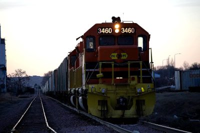 A photo of an orange and yellow freight train with the number "3460" written on it, at dusk in the midwest. Shot in the style of ARRIFLEX 25 BL Camera Canon K7 prime lens 8mm.