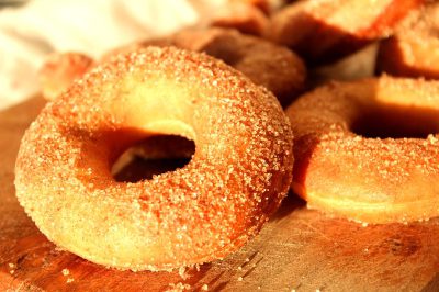 close up photo of sugar dusted donuts on wooden board, warm light, food photography, highly detailed