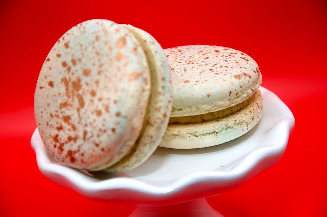 food photography of two macarons with speckles on top, white and red background, white plate, studio light,