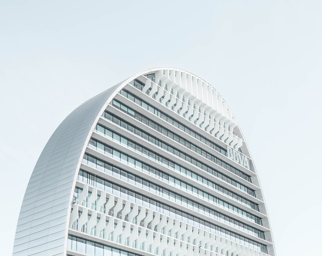 A curved white office building with large windows, architectural photography on archdaily, bright light in a minimalistic and high angle shot style, muted colors under an overcast sky with soft shadows, professionally color graded and isolated on a clean background, hyper realistic photography. –ar 64:51