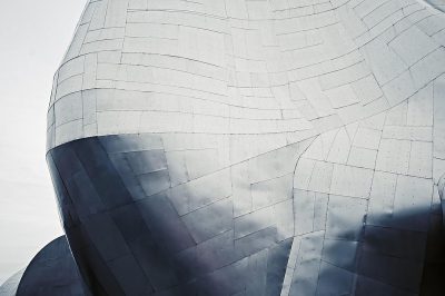 A close-up shot of the sleek, stainless steel exterior of [Frank Gehry](https://goo.gl/search?artist%20Frank%20Gehry)'s architecture at Disney plaster in Los Angeles. The photo captures intricate details and textures on its surface against a white sky background. Shot with a Sony Alpha A7R IV for sharp focus and depth. Soft natural lighting enhances the minimalist aesthetic. A Canon EF lens at 24mm f/8 was used.