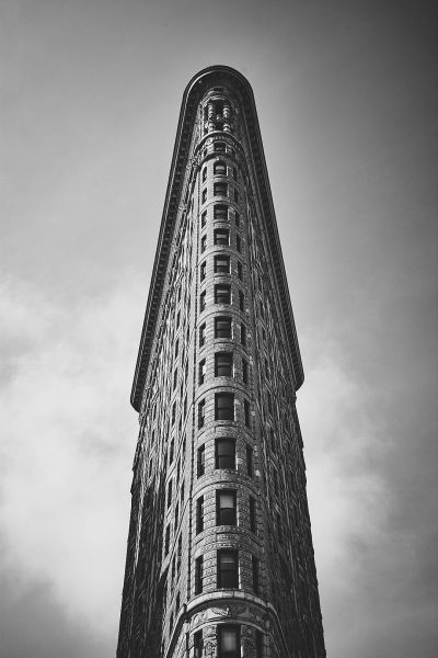Flatiron Building, New York City in the style of black and white photography, low angle perspective, symmetrical composition, vintage filter effect, wideangle lens, clear sky, cityscape background, iconic architecture.