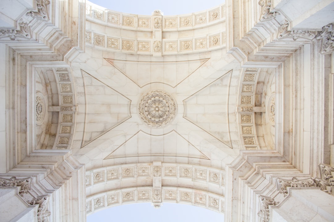 an arch in the sky of Lisbon, with intricate architectural details, the ceiling is made out of white marble and has an ornate geometric design, symmetrical, straight down view, professional photography, cinematic lighting, high resolution,