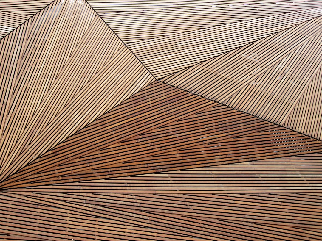 A closeup of the roof’s geometric pattern, showing how thin wooden strips form intricate patterns and textures that add depth to its design. The wood is natural with some subtle grain lines visible in each strip, giving it an organic feel while maintaining a modern aesthetic. This detail highlights one aspect of texture and shape on which your artistic focus will be placed in the style of your chosen artist.