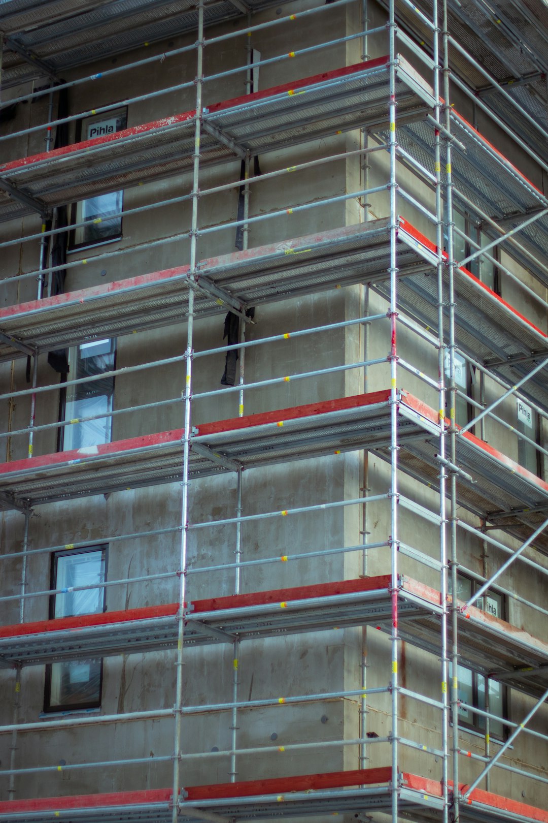 Scaffolding in the style of S&M on the side of an apartment building, with no people or equipment visible, featuring grey and red accents, captured as construction photography with a Nikon D850 camera using a Nikon AFS Nikkor 24-70mm f/3.6 lens. –ar 85:128