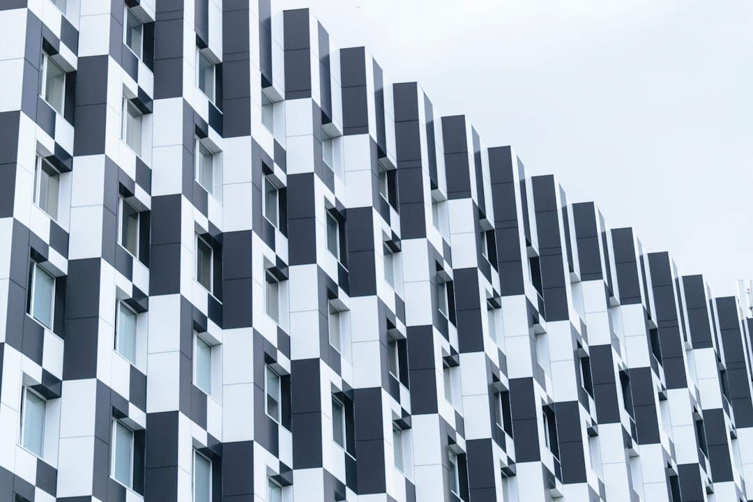 Modern building facade with black and white geometric patterned panels, creating an eyecatching visual effect against the clear sky. –ar 128:85