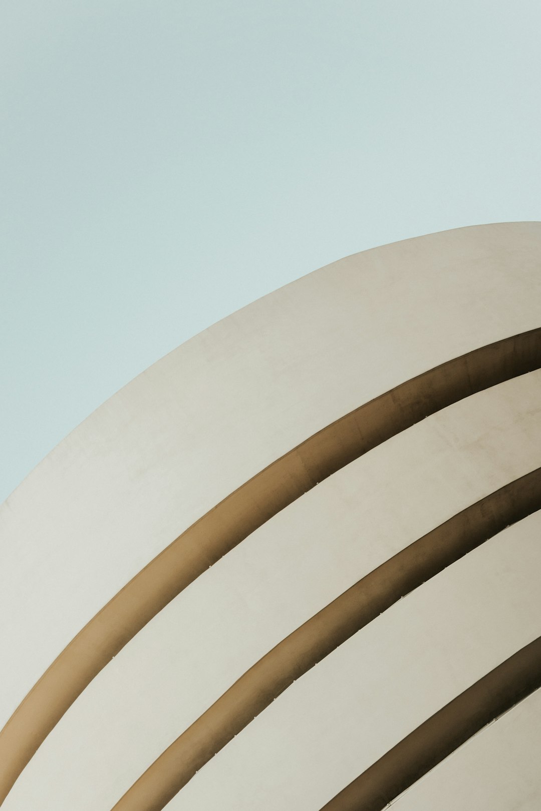 minimalist photo of G harbour, architecture photography by [Iwan Baan](https://goo.gl/search?artist%20Iwan%20Baan), beige and light blue sky, extreme low angle shot close up on the guggenheim museum in new york city, circular lines, minimal aesthetic, grainy –ar 85:128