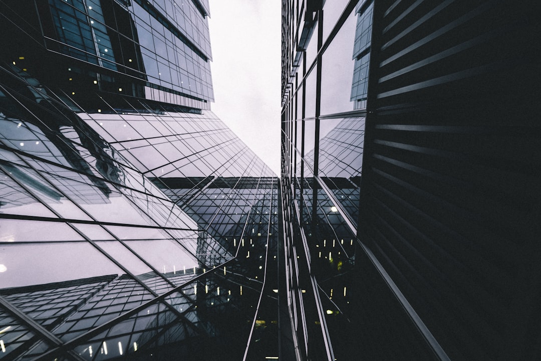 A wide angle photo of glass skyscrapers in a low angle shot with high contrast and muted tones that is moody, dark, cinematic and atmospheric with reflections in the windows. –ar 128:85