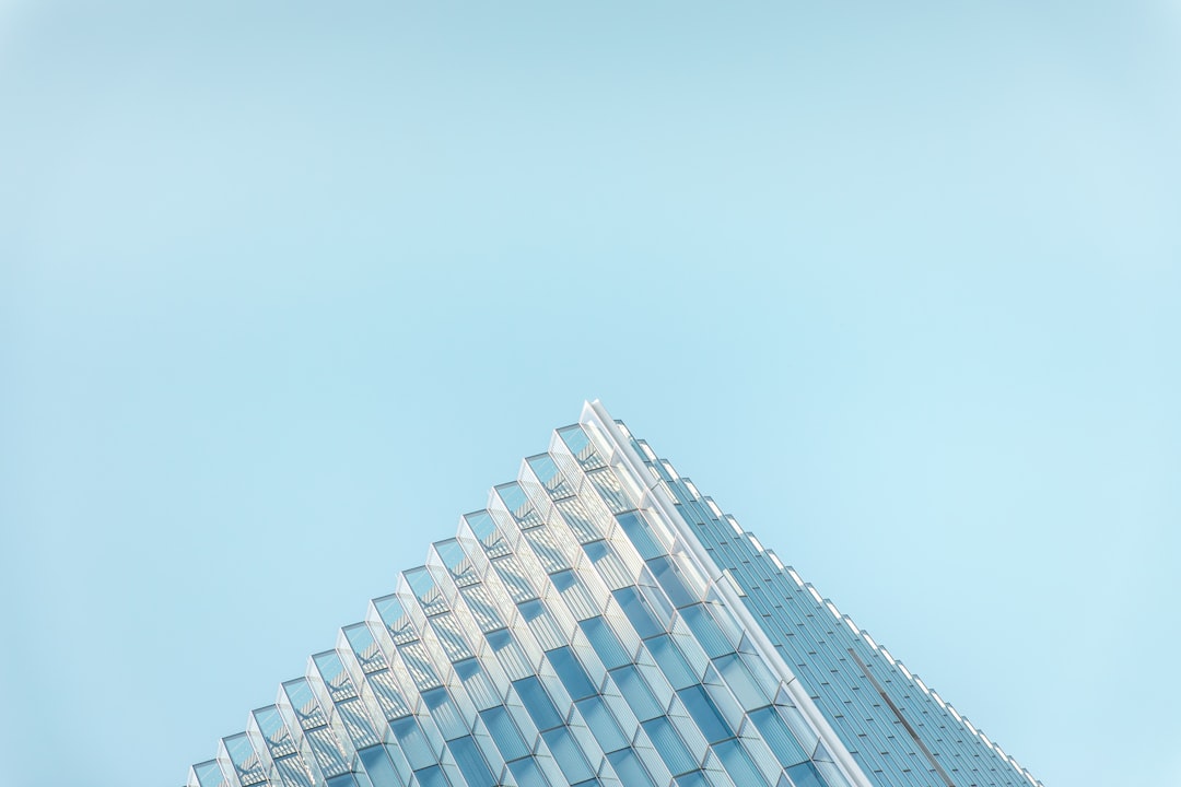 Minimalistic photography, glass building with triangular shape on clear blue sky background, low angle view, focus on the architecture details, shot by Hasselblad X2D, candid moment captured in natural light, natural tones, minimal aesthetic, contemporary style –ar 128:85