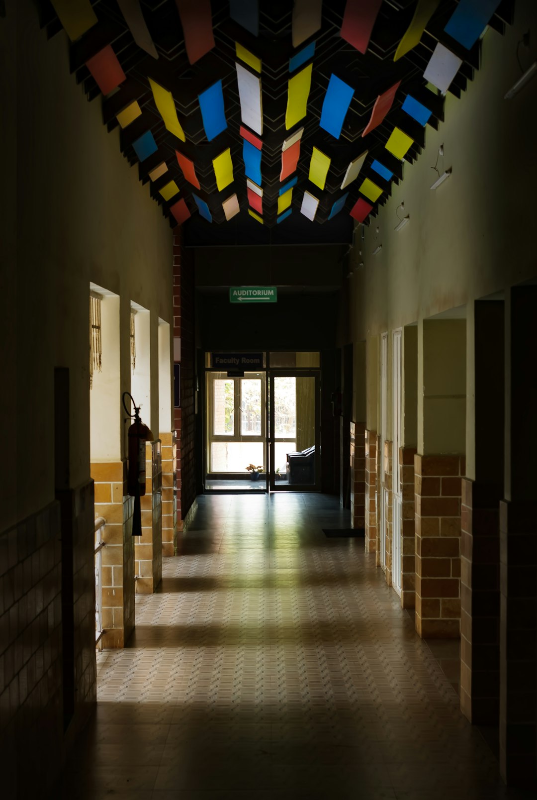 A hallway of an elementary school with a colorful ceiling made from cutout bricks, dark and moody in the style of hyper realistic photograph, photo taken on Canon EOS R5 F2 ISO100 89MM.