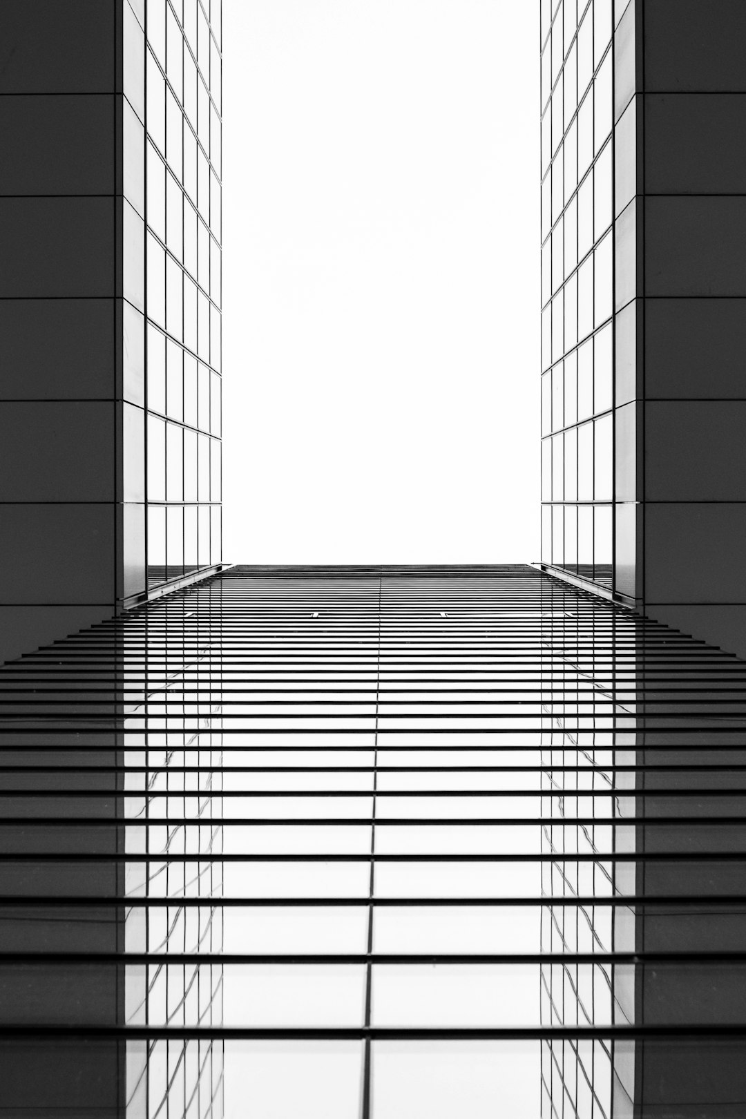 Minimalist black and white photography, modern architecture with glass windows, symmetrical composition with symmetrical lines, in the style of modern artists. –ar 85:128