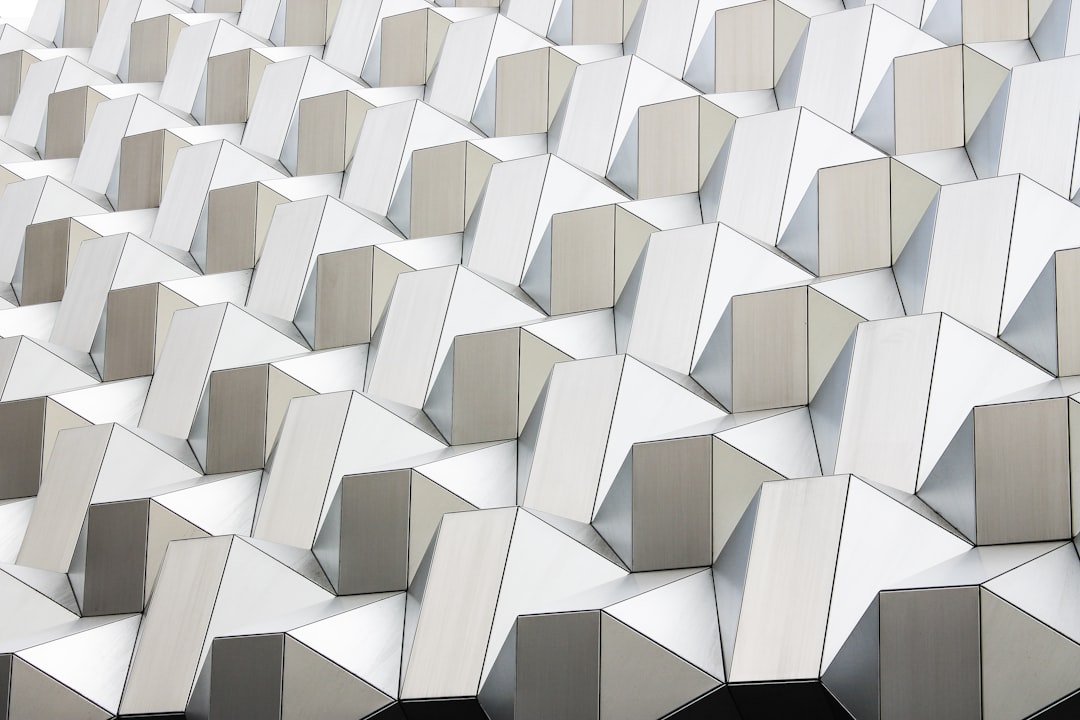 a close up of an exterior building facade made from white and grey metal panels arranged in the shape of hexagons, hyper realistic photography –ar 128:85