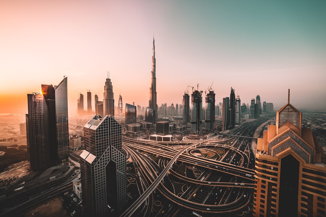 A wide-angle view of the Dubai skyline at sunrise, showcasing iconic buildings like Burj Khalifa and Zorias Tower with roads crisscrossing in the front. The sky is pastel-colored, creating soft lighting over modern architecture against an urban landscape. Shot on Canon EOS R5 mirrorless camera using a high-resolution macro lens for detailed photography. –ar 128:85