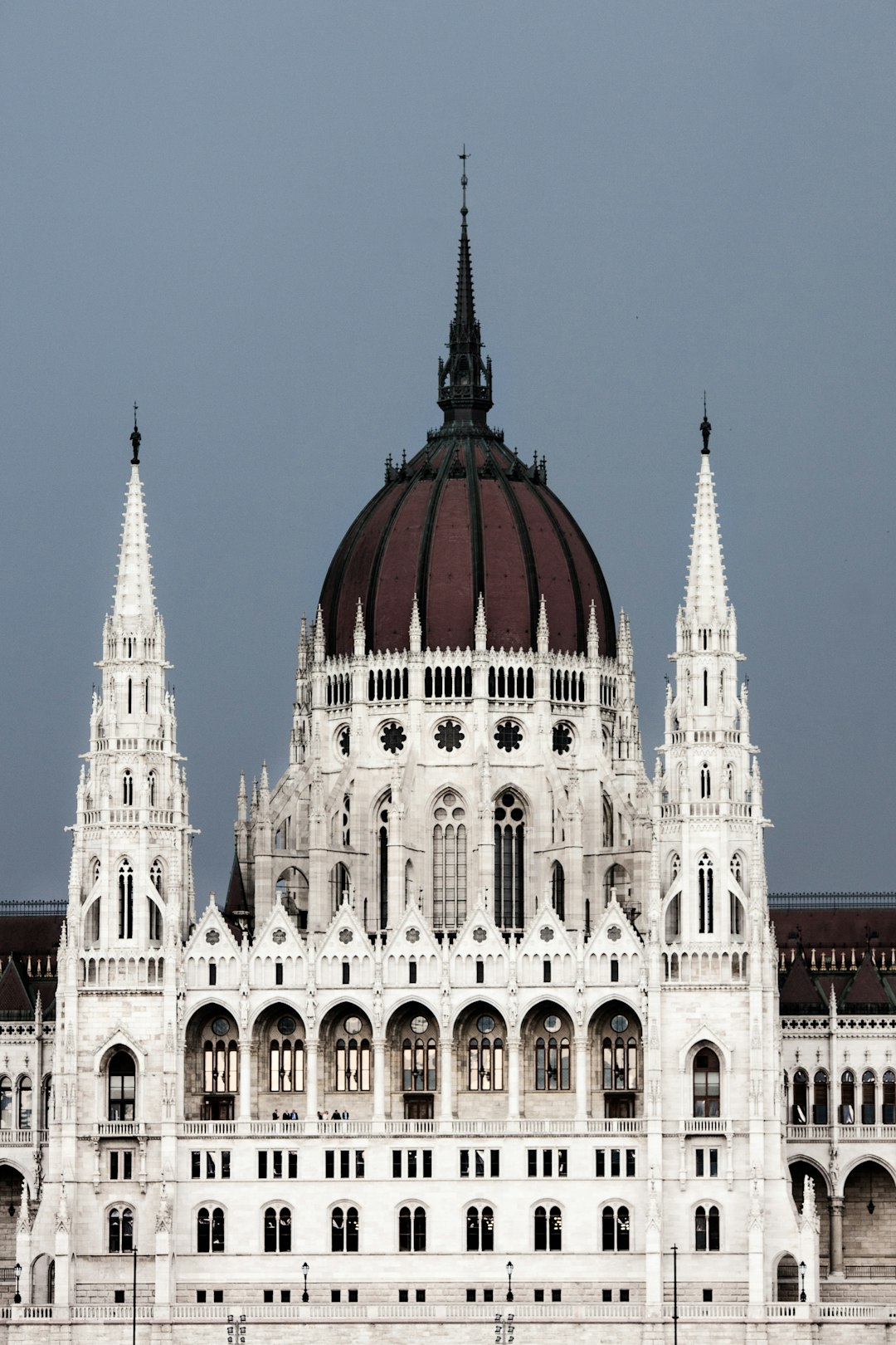 Photo of the parliament building in Budapest, with its intricate spires and domed roof, stands as an iconic symbol of the city. The white stone walls contrast beautifully against the dark grey sky. Captured in the style of Hasselblad H6D400c MultiShot camera for stunning detail. High resolution, sharp focus, cinematic lighting, global illumination, natural look. –ar 85:128