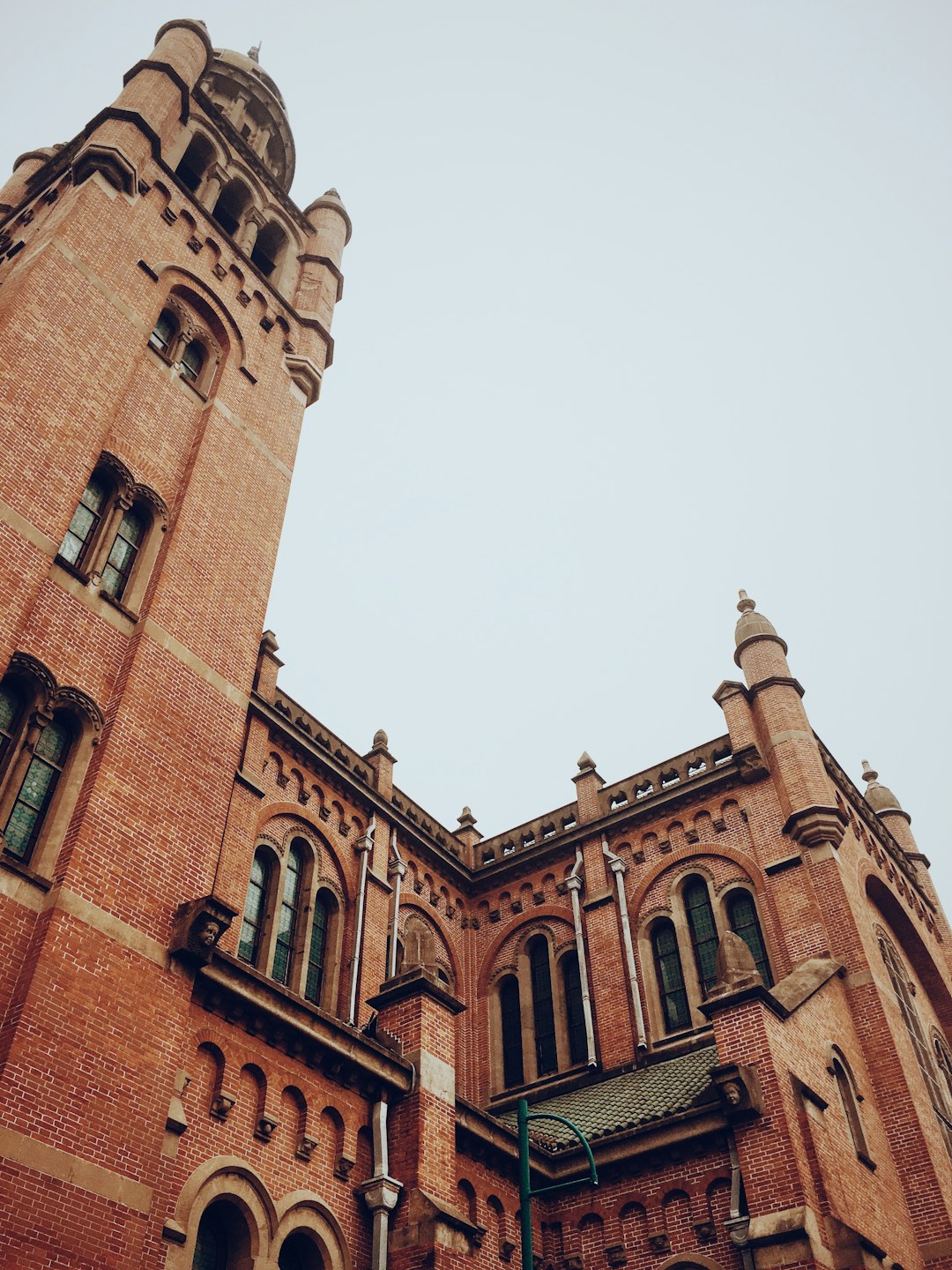 The red brick building of the stoic style, Gothic architecture features tower and spire with arched windows, low angle shot, photo taken by Canon EOS, using Fujifilm Superia XTRA 400 film stock –ar 3:4